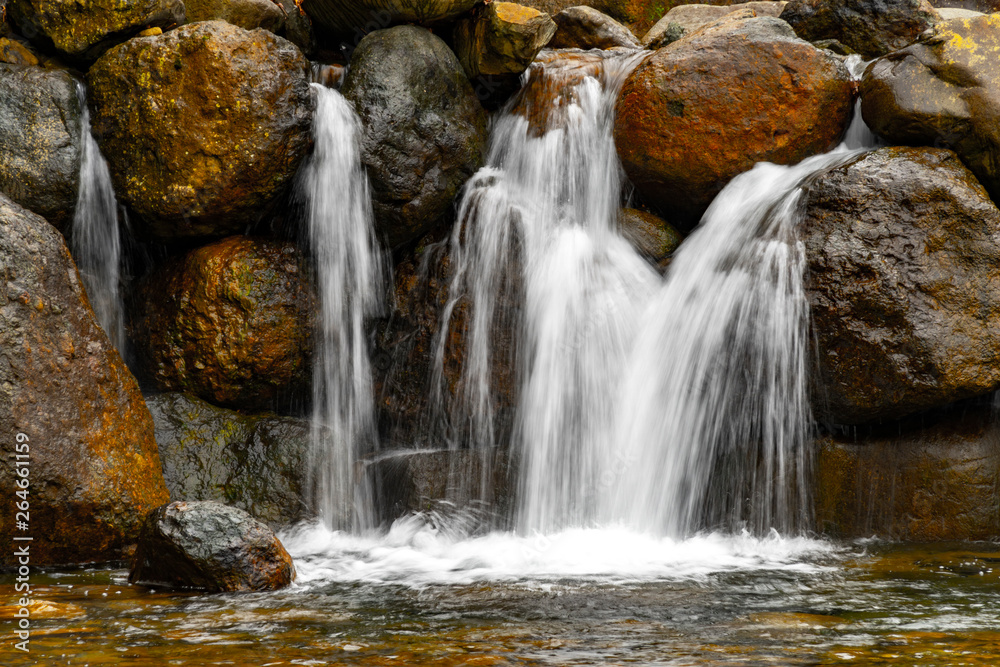 Fantastic landscape view of waterfall flowing around rocks with greens and stones in long exposure. Fantastic landscape view of waterfall flowing around rocks with greens and stones in long exposure.