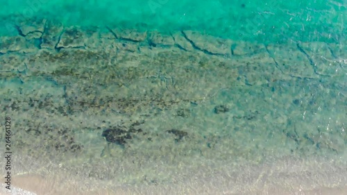 Aerial view of blue sea surface on sand beach with light reflections. Top view of transparent turquoise ocean water surface.