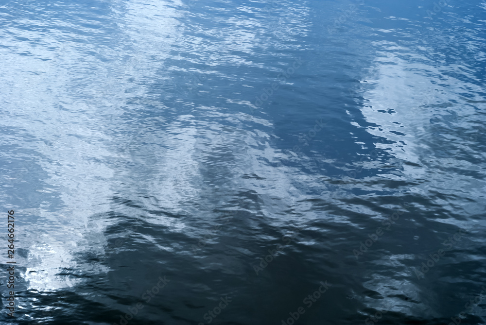 background - glossy water surface with waves and sky reflection