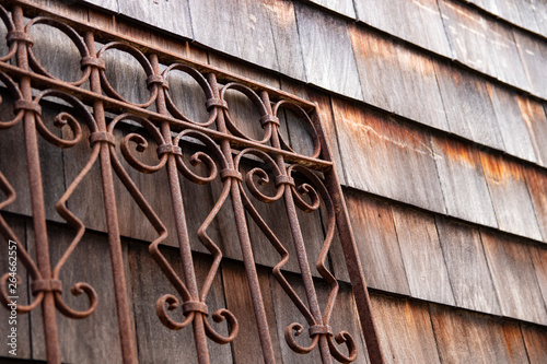 Weathered wood shingle siding and rusty wrought iron metal gate