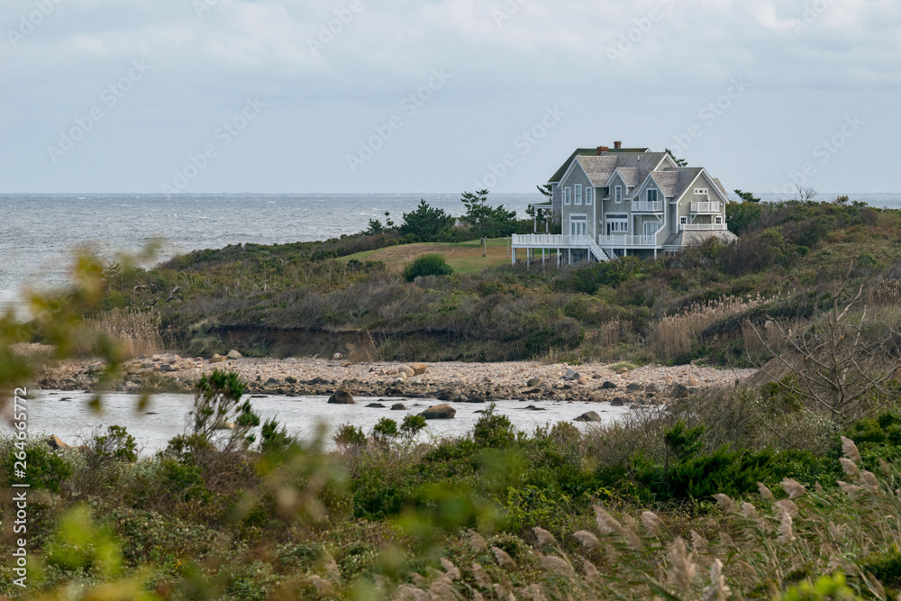 Small house among shrubs and grass, overlooking a rocky beach, Block Island, RI Small house among shrubs and grass, overlooking a rocky beach, Block Island, RI