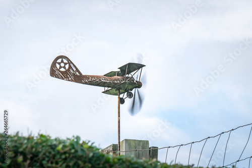 Weather vane in form of an old rusty biplane, at a side-view, with propellers moving