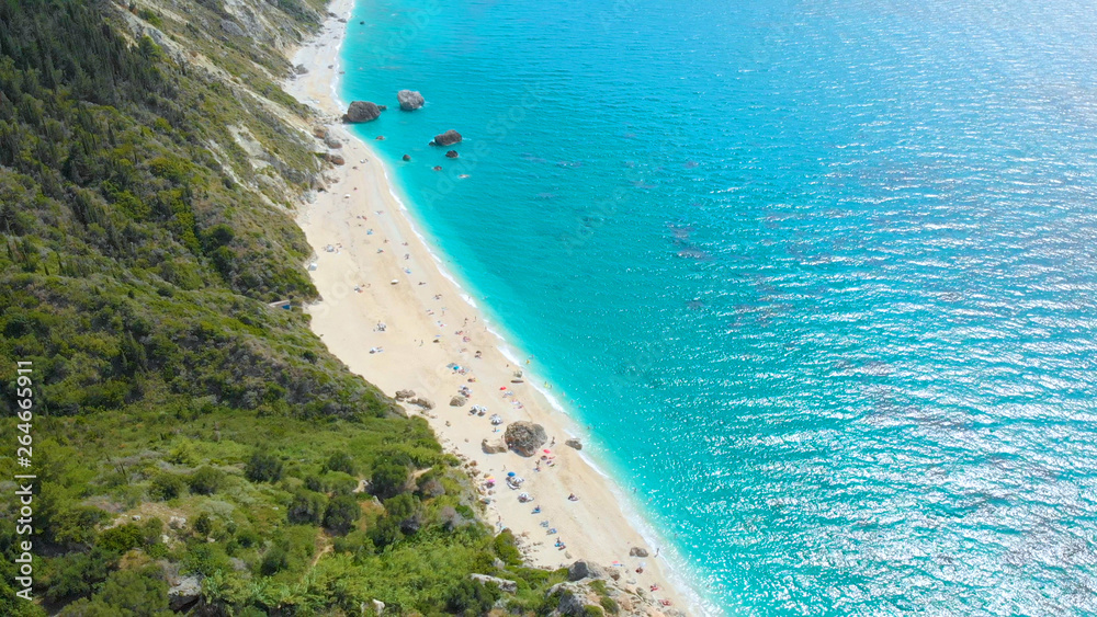 AERIAL: Stunning view from above of a remote white sand beach and turquoise sea.