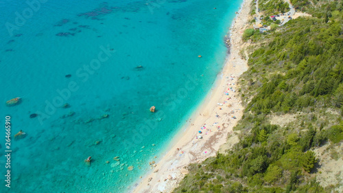 AERIAL: Flying above colorful deckchairs and umbrellas on the secluded beach.