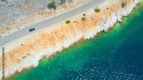 AERIAL  Flying along a tourist car cruising down empty coastal road on sunny day