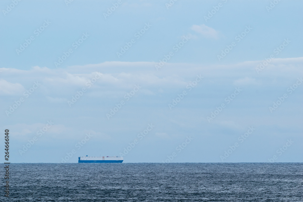 Cargo ship on calm water, crossing the horizon on a beautiful sunny day