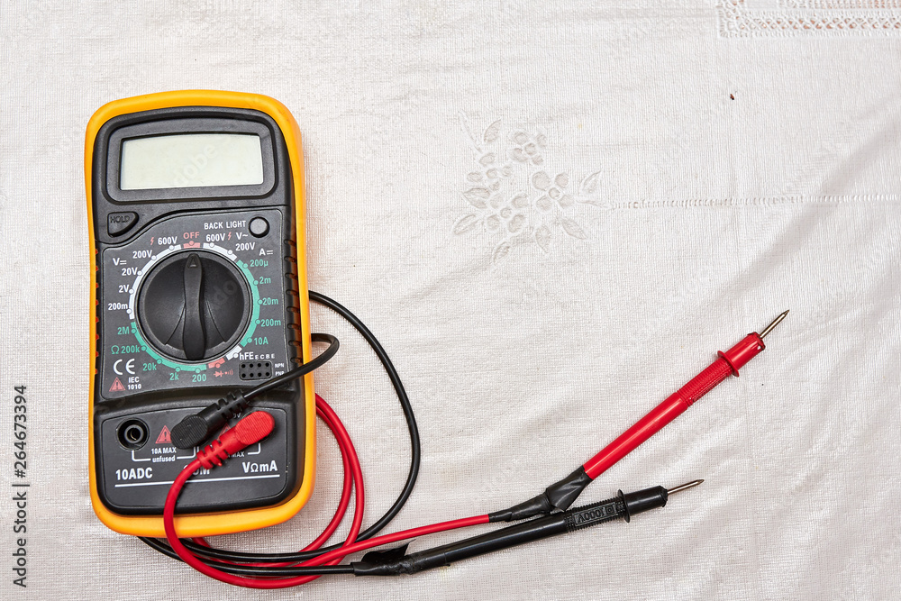 Classic multimeter in orange case with two probes on a white background. flat lay. copy space Classic multimeter in orange case with two probes on a white background. flat lay. copy space