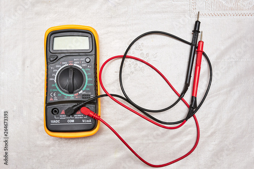 Classic multimeter in orange case with two probes on a white background. flat lay. copy space