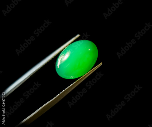 Natural Chrysoprase Gems Stone oval cut beautiful.Holding a green stone by tweezers.