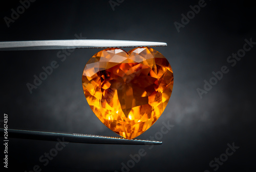 Natural madeira citrine Gems Stone oval cut beautiful.Holding a yellow stone by tweezers.