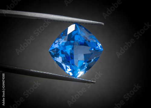 Natural Swiss Blue Topaz Cushion Shape Gems Stone oval cut beautiful.Holding a blue stone by tweezers.