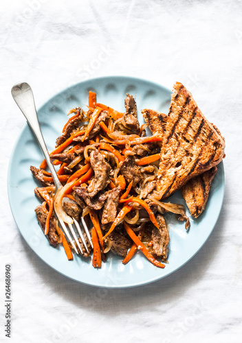 Spicy fried beef wok with carrots on a light background, top view