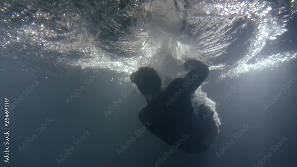 a man in clothes falls back into the water. underwater shooting of a drowning man