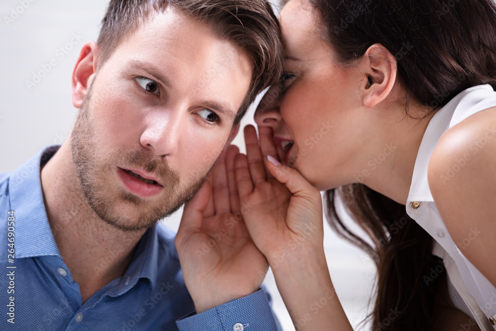 Businesswoman Whispering Into Partner's Ear Businesswoman Whispering Into Partner's Ear