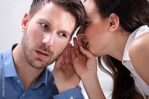 Businesswoman Whispering Into Partner's Ear