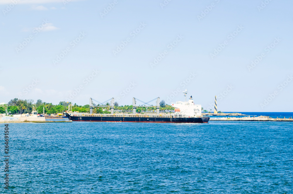 cargo boat arriving at the entrance of the port of Santo Domingo, Dominican Republic with a tropical blue sea