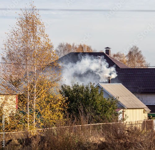 Smoke from the chimney on the roof of the house