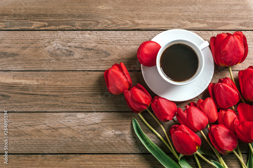Row of red tulips and cup of black coffee americano on wooden background with space for text, message. Mother's Day, Hello spring, good morning concept. Card. Flat lay. Top view. Rustic style. 