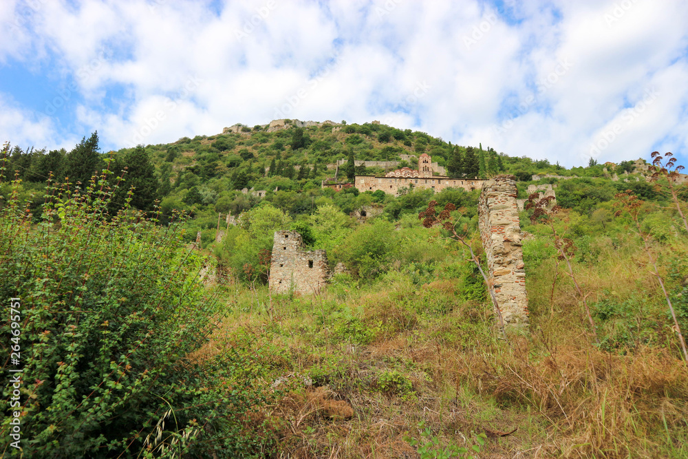 Beautiful panoramic view to abandoned byzantine town Mystras on the hill with blue sky on the background, Greece