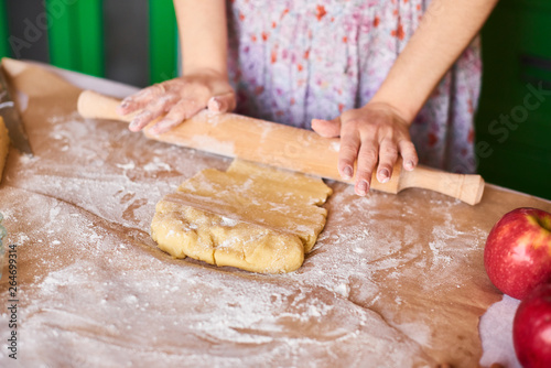 Woman kneading dough for the apple pie on kitchen table. Rustic style