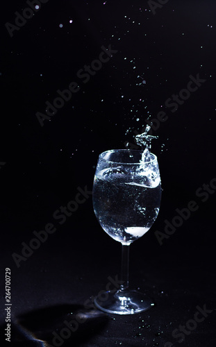 Transparent glass of water in the foreground on a black background