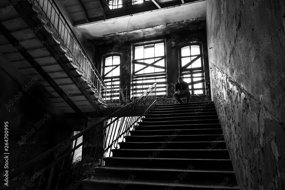 Fototapeta premium Silhouette of man sitting on stairs in ruined place.
