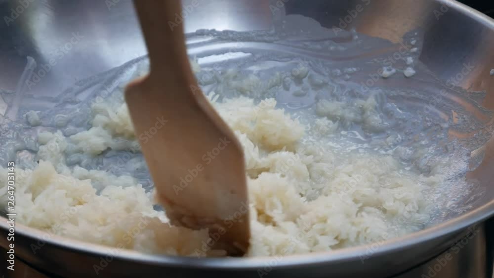 Male hand stir rice with coconut milk in wok. Step by step cooking Thai sticky rice. Thai cuisine. Closeup. 4k Male hand stir rice with coconut milk in wok. Step by step cooking Thai sticky rice. Thai cuisine. Closeup. 4k