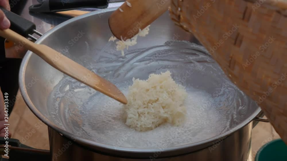 Male hand stir rice with coconut milk in wok. Step by step cooking Thai sticky rice. Thai cuisine. Closeup. 4k Male hand stir rice with coconut milk in wok. Step by step cooking Thai sticky rice. Thai cuisine. Closeup. 4k