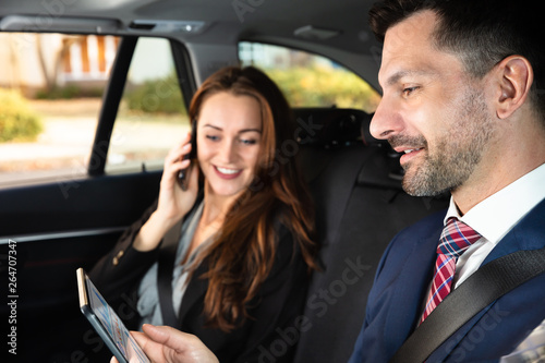 Businesswoman Sitting Inside Car Beside Her Male Colleague