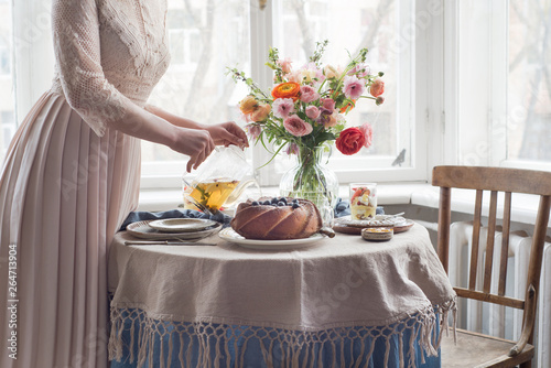Tea time, Woman hands holding tea pot, flowers and cake