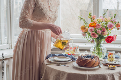 Tea time, Woman hands holding tea pot, flowers and cake