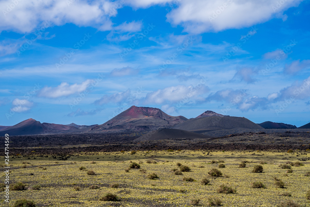 Spain, Lanzarote, Colorful volcano mountains of timanfaya national park behind black and green lava fields