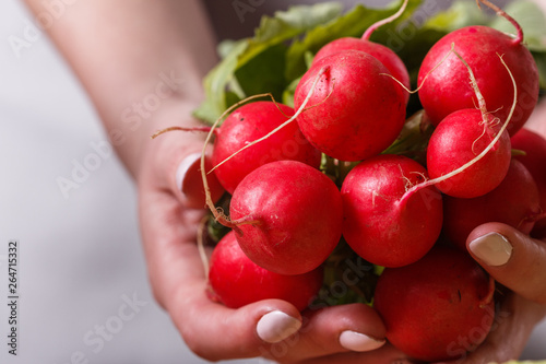 young woman in a gray apron cuts a radish
