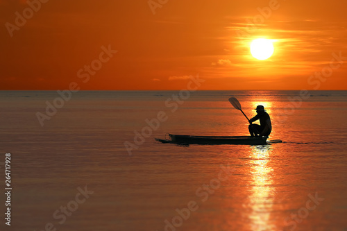 Silhouette of Local fishermen rowing small boats along the coast by the beach red sky sunset © THANAGON