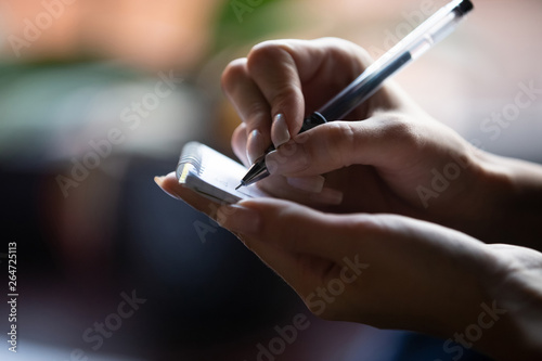 Close up hand of waitress holding pen and notepad writing visitor order