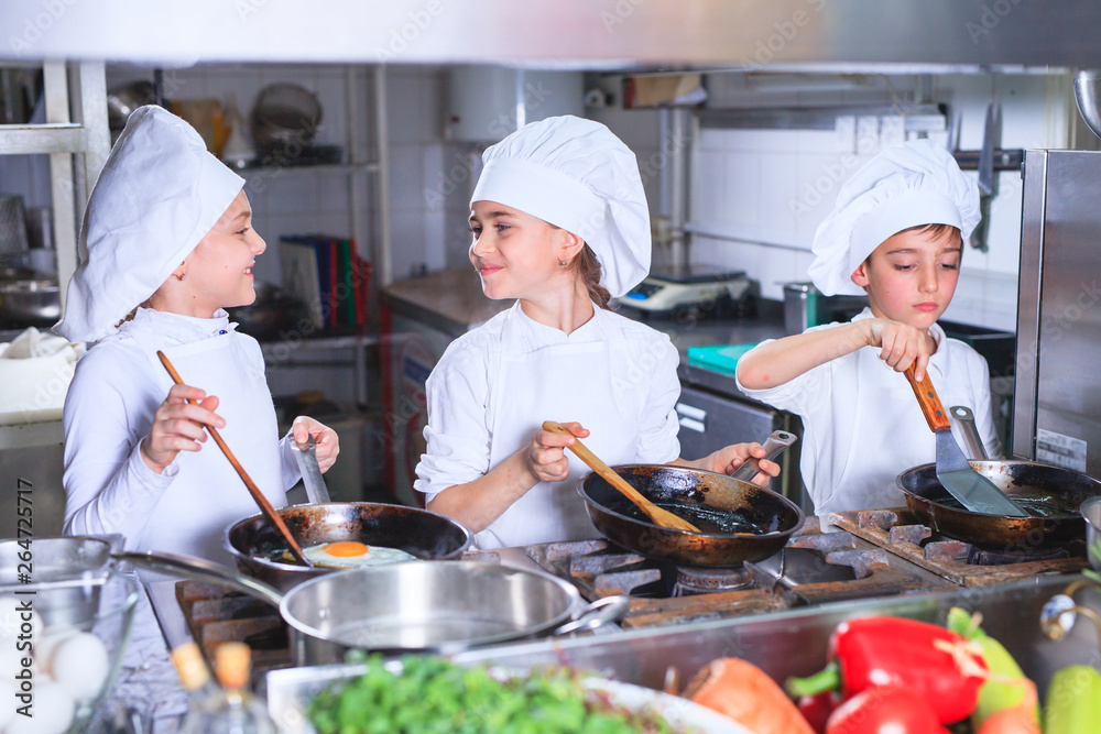 children cooking lunch in a restaurant kitchen. children cooking lunch in a restaurant kitchen.