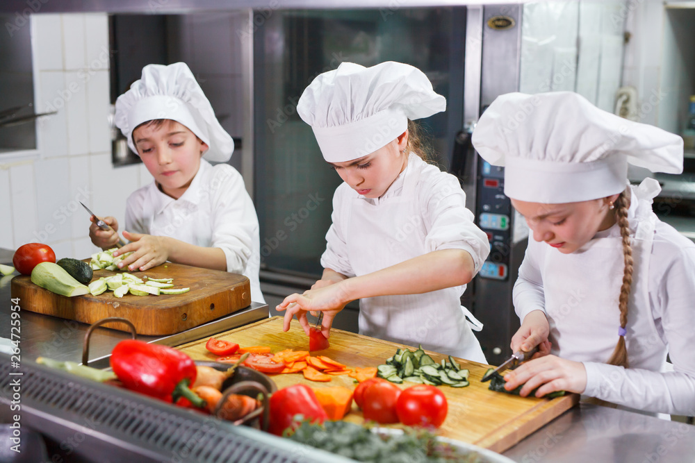 children cooking lunch in a restaurant kitchen. children cooking lunch in a restaurant kitchen.