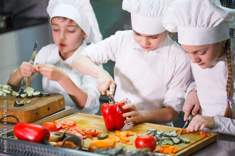 children cooking lunch in a restaurant kitchen. children cooking lunch in a restaurant kitchen.