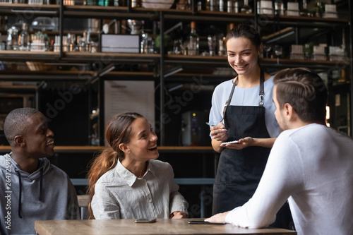Foto Diverse friends sitting in restaurant placing order talking with waitress