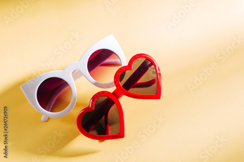 Set of Stylish sunglasses with bright sunlight on yellow background. Flat lay, top view. Summer fashion concept