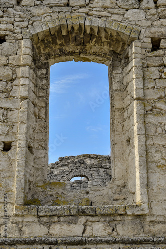 Dilapidated ancient synagogue. View of the sky and the wall through the arched window. The texture of old dilapidated masonry. Stones covered with moss. Rashkov  Moldova. Selective focus.