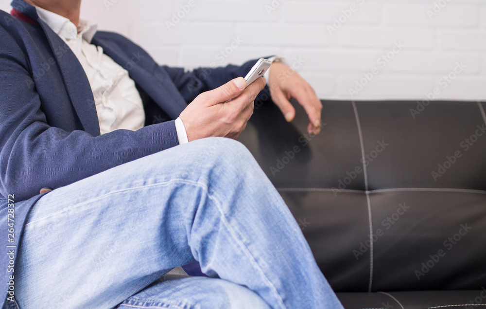 Fototapeta premium businessman sitting on the couch with mobile phone