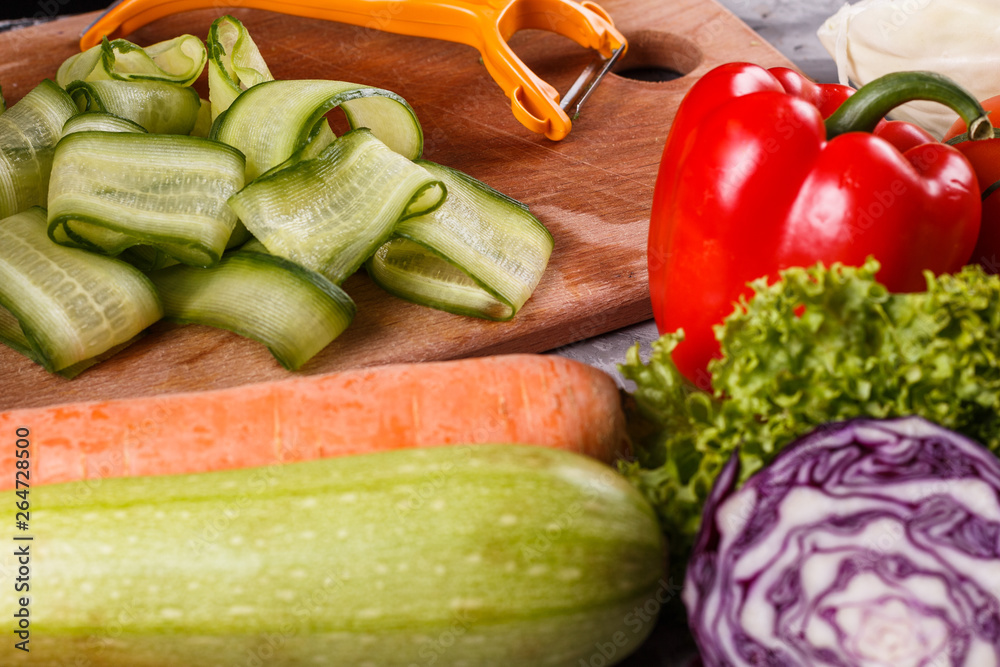 young woman in a gray apron cuts a cucumber