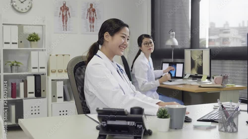 slow motion of young female doctor done work great while working on computer showing pointing finger to colleague. two medical girl staff cheerfully laughing happy with hands in fist yes expression. slow motion of young female doctor done work great while working on computer showing pointing finger to colleague. two medical girl staff cheerfully laughing happy with hands in fist yes expression.