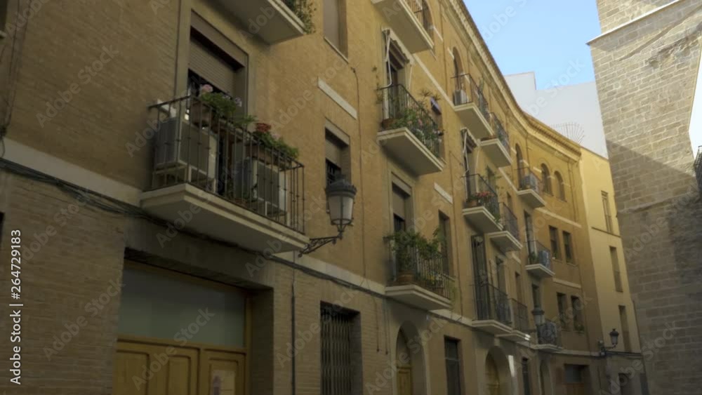 Camera pans left from building next to the cathedral to a side wall of the Cathedral of Valencia, with the arched bridge which connects the two buildings . Camera pans left from building next to the cathedral to a side wall of the Cathedral of Valencia, with the arched bridge which connects the two buildings .