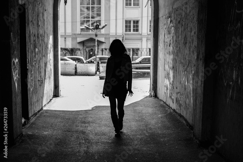 Black and white photo, silhouette of a girl in the architectural arch of the tunnel