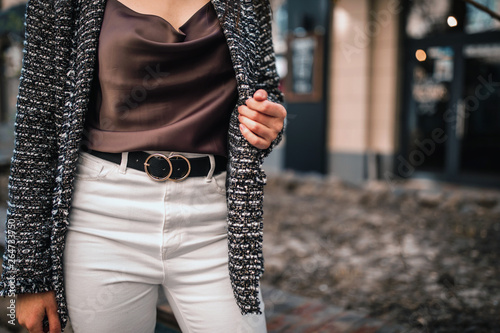 Street, office, bright style. Young woman in black jacket, white pants with a black belt