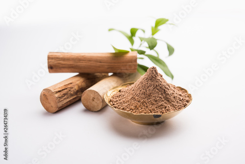 Chandan or sandalwood powder with sticks and green leaves photo