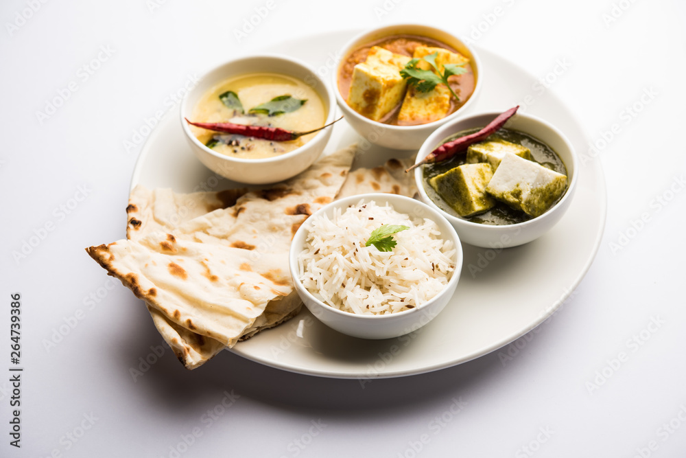 Indian vegetarian platter / Thali having Palak paneer butter masala, dal makhani, flat bread or naan and rice served in a white plate Indian vegetarian platter / Thali having Palak paneer butter masala, dal makhani, flat bread or naan and rice served in a white plate