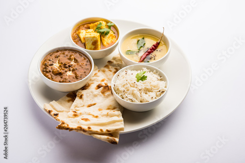 Indian vegetarian platter / Thali having Palak paneer butter masala, dal makhani, flat bread or naan and rice served in a white plate